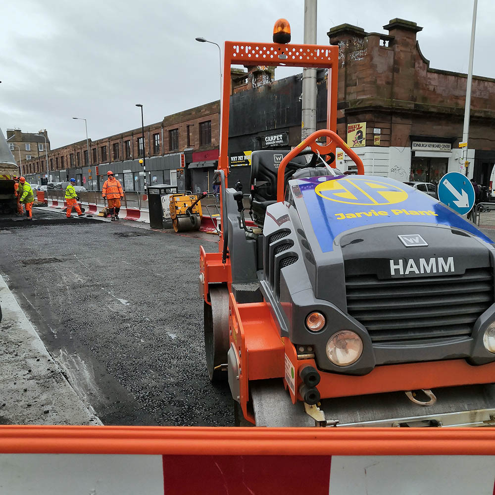 Close up of tarmac rolling vehicle with construction workers