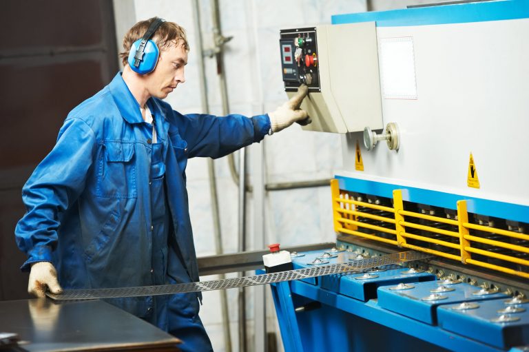 Manufacturing worker using moving machine to cut sheet metal - broken arm