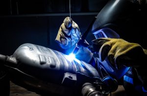 Employee of vehicle repair workshop welding car part