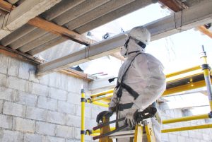 Construction worker handling asbestos removal in a building with PPE
