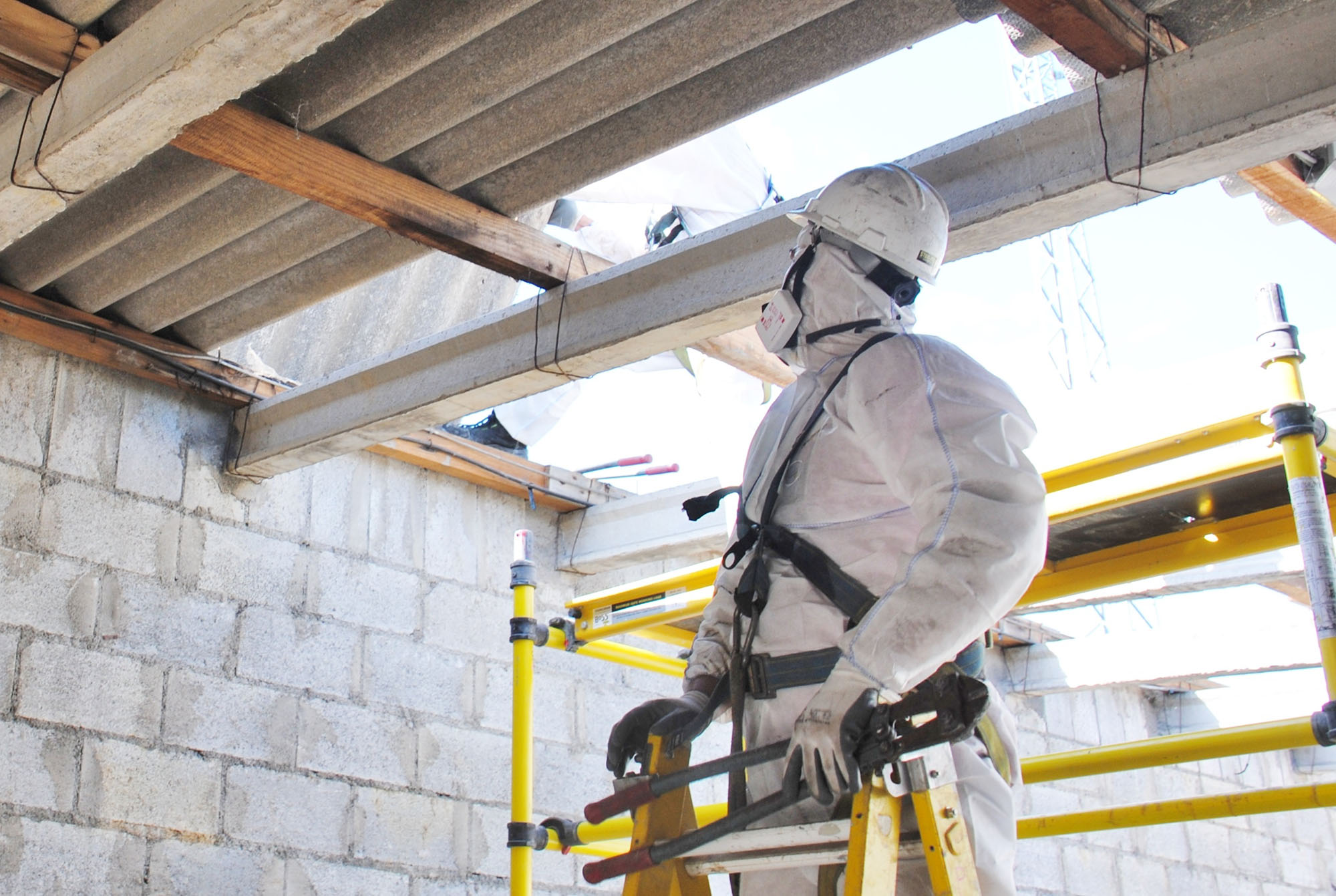 Construction worker handling asbestos removal in a building with PPE